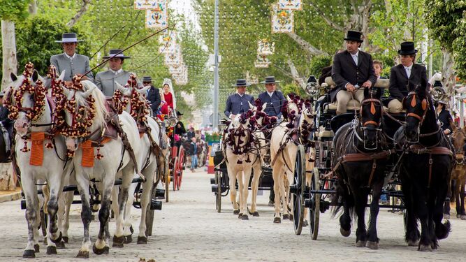 Coches de caballo pasean por una calle del real de la Feria.