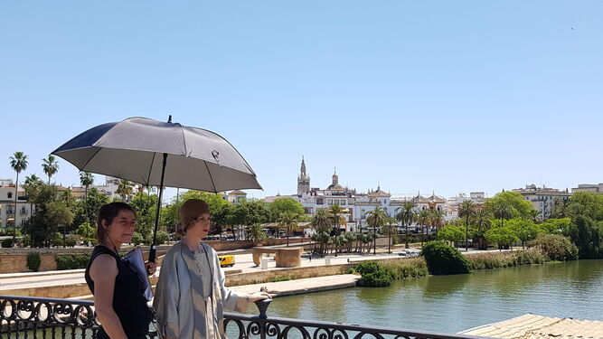 Cecilia Freire se resguarda bajo un paraguas en el Puente de Triana durante el rodaje.
